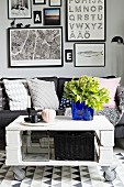 White and grey seating area with sofa, royal blue glass vase as focal point on DIY coffee table on castors and gallery of pictures in background
