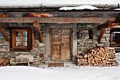Winter atmosphere - rustic stone house with firewood stacked against facade