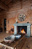 Rough bowl made of natural material on rustic wooden coffee table in front of open fire in cabin interior
