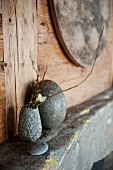 Flowering twigs in stone vase and egg-shaped stone on vintage shelf