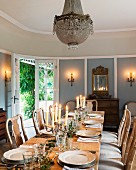 Lit candles on festively-set table and walls in dining room with traditional, country-house atmosphere