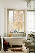 Narrow bathroom with free-standing bathtub and twin sinks in historical English town house with lattice window