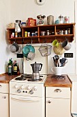 Vintage electric cooker flanked by kitchen base units: wooden shelves of spices and kitchen utensils on wall