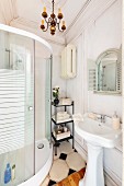 Vintage pedestal sink opposite modern, curved, glass shower cabinet in traditional bathroom with wood-clad wall and stucco frieze on ceiling
