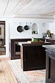 Freistehende Theke zwischen Küchenzeilen aus dunklem Holz in rustikaler Küche mit Holzdecke