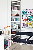 Classic chair below artwork in style of Keith Harings next to shelves in niche with sliding door
