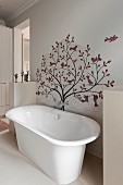 Free-standing bathtub below artistic mosaic of tiles on wall