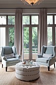 Two armchairs and pale ottoman in front of French windows