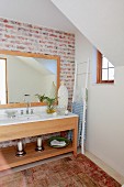 Modern washstand with framed mirror against exposed, vintage-style brick wall
