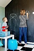 Child drawing on wall painted with blackboard paint