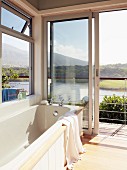 Bathtub with magnificent view of South African lagoon landscape through open terrace doors