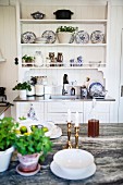 Potted herbs on counter opposite decorative, blue and white painted plates on dresser in rustic interior