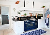 Blue rug in front of kitchen counter with blue, retro cooker and integrated extractor hood