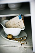Vintage Messing Docht-Schere neben Briefen in Sauciere aus weißem Porzellan