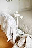 Ornate, white-painted, metal valet stand at foot of bed