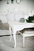 Candles on white-painted coffee table with curved legs and upholstered footstool in front of sofa