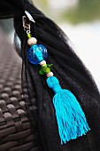 Oriental, light blue tassel threaded with beads on black mosquito net