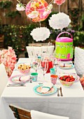 Party table set with brightly patterned plastic and paper tableware in garden