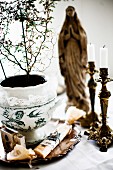 Zimmerpflanze mit bemaltem Porzellan Übertopf und antike Kerzenhalter, im Hintergrund Madonna Figur
