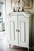 White-painted cabinet with feet below framed pictures on wall