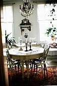 Round dining table and chairs with turned legs painted white in rustic interior