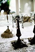 White candles in antique candlesticks with beaded ornaments on tablecloth