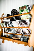 Magazines in carved wooden rack on white wooden wall