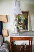 Table lamp with cherub base on wooden bedside table with marble top