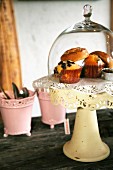 Muffins under glass cover on vintage, pastel yellow cake stand