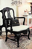 Black handbag on black-painted armchair with white seat cushion in Wilhelmine style