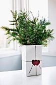 Fir branches in cubic vase with love-hearts on gift ribbon decoration