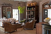 Wicker chairs and sofa on sisal rug in living room decorated in warm, earthy shades