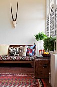 Sofa with ethnic scatter cushions below hunting trophy in living room with Moroccan ambiance