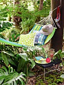 Hammock with cushions and sun hat next to drink on stool