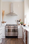 Stainless steel gas cooker and extractor hood in modern kitchen