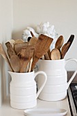 Wooden cooking utensils in white ceramic jugs
