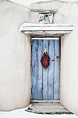 Traditional chili ristra hanging on closed door; Santa Fe; New Mexico; USA