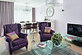 Sitzbereich im eleganten Stilmix mit klassisch gemusterten Ohrensesseln im Violett und modernem Acrylglastisch