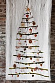 Stylised Christmas tree made from mossy branches with festive decorations hanging on white cloth