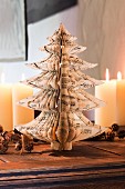 Selbstgebastelter Weihnachtsbaum aus zerschnittenen Notenblättern, dahinter brennende Kerzen und Zapfengirlande