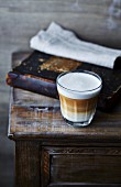 Glass of latte macchiato coffee on old cabinet