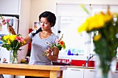 Young woman arranging flowers in kitchen