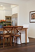 Offener Wohnraum mit Esstisch & verschiedenen Stühlen sowie Durchgang zur Küche