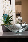 Moderner Waschtisch mit Waschschale aus Glas & Orchideen als Blumendeko
