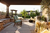 Überdachte Terrasse mit Stühlen & dekorativer Grasbepflanzung