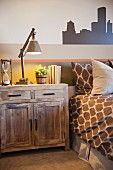 Schlafzimmer in Brauntönen mit Holzkommode als Nachttisch & Schablonenmalerei an Zimmerwand