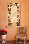 Antiker Holzstuhl & Pokalgefäss mit Blumen vor Wand mit dekorativen Fliesenmotiv