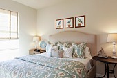 Schlafzimmer in Beige mit hellblauen Farbakzenten, Doppelbett, Nachttischen & Wandbildern mit Vogelmotiven