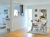 Bright dining area with various rugs on flokati rug and partition wall with aperture to kitchen; country-house ambiance