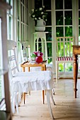 Traditionelle Küchenstühle, weiss lackiert, vor raumhohen Sprossenfenstern